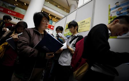 Job hunters fill in application forms during a job fair in Hong Kong, south China, on March 11, 2009.