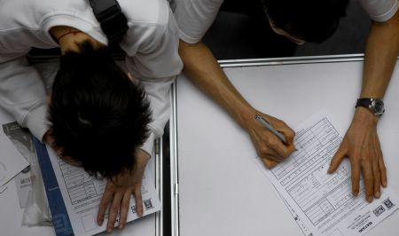 Job hunters fill in application forms during a job fair in Hong Kong, south China, on March 11, 2009. 