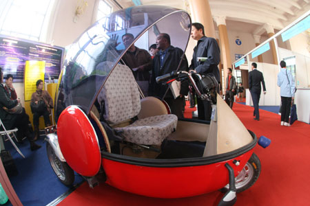 Visitors view an electric vehicle during the China International Energy Saving, Emission Reduction and New Energy Science and Technology Expo at the Beijing Exhibition Center in Beijing, capital of China, on March 22, 2009. More than 200 companies and organizations took part in the five-day expo, opened on March 19.