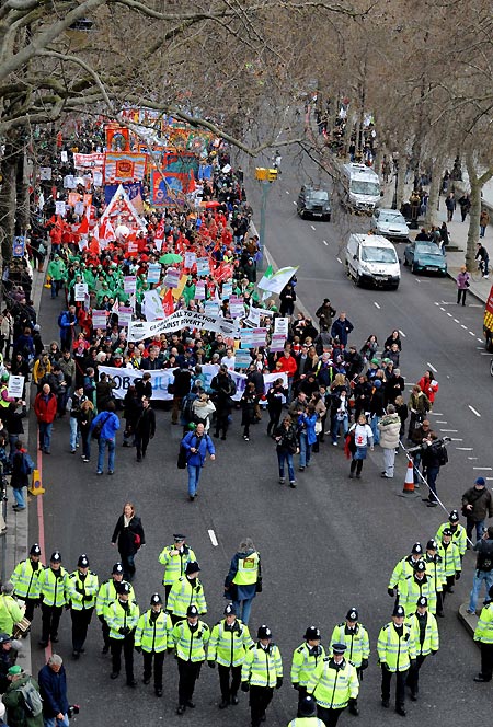 Police officers keep order in front of a procession of demonstrators in London on March 28, 2009. The Put People First group, an alliance of more than 150 unions, on Saturday organized the demonstration, calling on the leaders of the Group of 20 Countries (G20) to adopt sustainable policies that can lead the world out of recession. The demonstrators also urged the leaders to attach importance to global environment protection and to stablize the world political situation. 