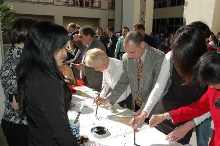 Visitors learn Chinese calligraphy during the unveiling ceremony for the Confucius Institute at San Diego State University, in southern California, the United States, on March 26, 2009. The Confucius Institute, jointly set up by by San Diego State University and China's Xiamen University, was unveiled on Thursday. 