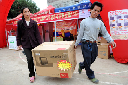 Two farmers carry their new television out of a household electrical appliances market in Shatian Town of Hezhou City, southwest China's Guangxi Zhuang Autonomous Region, on March 27, 2009. Over 10 dealers were organized to send household electrical appliances to markets in remote areas these days, offering farmers convenience to buy appliances. 