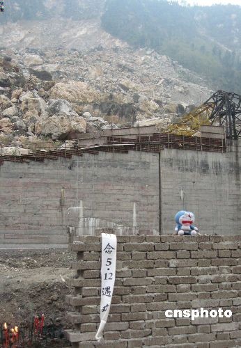A toy bear sits on a brick wall along with a mourning message at the foot of a collapsed mountain slope in Beichuan County, southwest China's Sichuan Province.