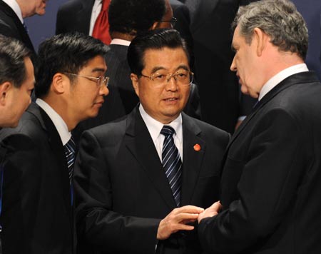 Chinese President Hu Jintao (2nd R) talks with British Prime Minister Gorden Brown (R) as they prepare to pose for a family photo during the Group of 20 summit in London, Britain, on April 2, 2009. 