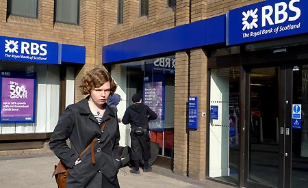 File photo taken on March 21, 2009 shows a woman walking past a branch of the Royal Bank of Scotland (RBS) in London, Britain. RBS said on April 7 that it might cut up to 9,000 jobs over the next two years, including 4,500 in the UK, in order to reduce cost. 