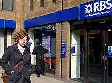 File photo taken on March 21, 2009 shows a woman walking past a branch of the Royal Bank of Scotland (RBS) in London, Britain. RBS said on April 7 that it might cut up to 9,000 jobs over the next two years, including 4,500 in the UK, in order to reduce cost.