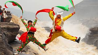 Two performers spring up during a highprofile tour-entertaining waist drum dance on the Hukou (Kettle Mouth) Waterfall on the Yellow River, in Yichuan, northwest China's Shaanxi Province, on April 12, 2009. The scenery zone of Hukou Waterfall has been reopened to tourists as of April 1 after a moratorium on account of unprecedented ice floes jam on the Yellow River in early January.