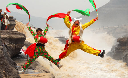 Two performers spring up during a highprofile tour-entertaining waist drum dance on the Hukou (Kettle Mouth) Waterfall on the Yellow River, in Yichuan, northwest China&apos;s Shaanxi Province, on April 12, 2009. The scenery zone of Hukou Waterfall has been reopened to tourists as of April 1 after a moratorium on account of unprecedented ice floes jam on the Yellow River in early January.