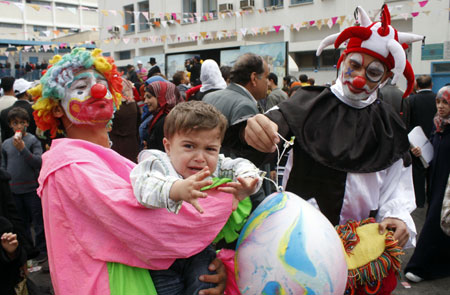 A dressed-up Palestinian holds a kid while attending a recreational day organized by the United Nations Relief and Works Agency (UNRWA) in Gaza City, on April 16, 2009. 