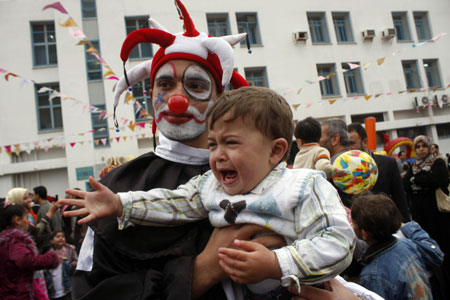 A dressed-up Palestinian holds a kid while attending a recreational day organized by the United Nations Relief and Works Agency (UNRWA) in Gaza City, on April 16, 2009. 