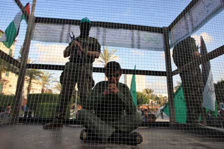 Palestinians act out a scene where a Hamas militant guards Israeli soldier Gilad Schalit, who was captured by Hamas-allied militants in Gaza in 2006, during a demonstration calling for the release of Palestinian prisoners in Israeli jails, in Gaza City, on April 16, 2009. 