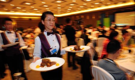 A waitress serves at the Luncheon Session of 'Time for a Green New Deal' during Boao Forum for Asia (BFA) Annual Conference 2009 in Boao, a scenic town in south China's Hainan Province, on April 19, 2009. Staff members and volunteers provided pleasant services for over 1,600 participants during the three-day BFA Annual Conference 2009 which concluded here on Sunday. 