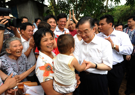 Chinese Premier Wen Jiabao (Front, R) holds a baby's hand during a visit to Benli Village in Haikou, south China's Hainan Province on April 19, 2009. Wen was on an inspection tour on the island province from April 18 to 19.