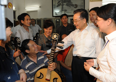 Chinese Premier Wen Jiabao (3rd, R) talks with a resident playing a folk instrument at a residential community in Haikou, south China's Hainan Province, on April 18, 2009.