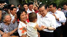 Chinese Premier Wen Jiabao (Front, R) holds a baby's hand during a visit to Benli Village in Haikou, south China's Hainan Province on April 19, 2009. Wen was on an inspection tour on the island province from April 18 to 19.