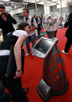 Visitors look at a shopping-guide robot during the 'Hannover Messe' industrial trade fair in Hanover, Germany, on April 20, 2009. The shopping-guide robot, which is said to be the first of its kind in the world, was designed by German scientists. It is a 1.5-meter tall, 75 kg weight robot that can help shoppers shopping.