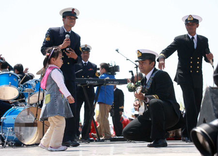 A little girl dances as members of Bangladeshi navy's military band perform during a performance in Qingdao, east China's Shandong Province, on April 21, 2009.