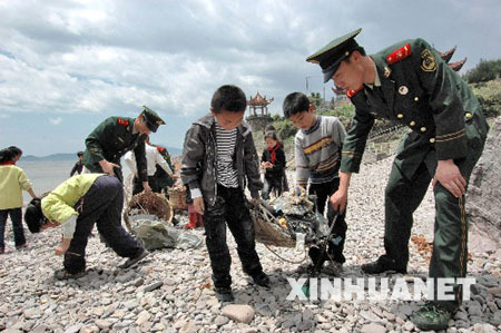 Soldiers and students collect garbage on a beach in Wenzhou, Zhejiang Province, on April 20, 2009. The Earth Day, celebrated on every April 22, is a day designed to inspire people's awareness and appreciation for the Earth's environment. 