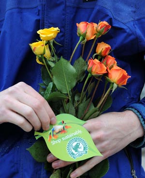 A volunteer of the U.S.-based conservation group Rainforest Alliance holds flowers and a card written 'shop sustainbaly' at the Union Sqaure in New York, the United States, on April 22, 2009. Volunteers here on Wednesday distributed flower seeds and cards with tips about environment protection to passersby to mark the annual Earth Day. 
