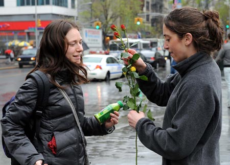 A volunteer (R) of the U.S.-based conservation group Rainforest Alliance sends flowers to a pedestrian at the Union Square in New York, the United States, on April 22, 2009. Volunteers here on Wednesday distributed flower seeds and cards with tips about environment protection to passersby to mark the annual Earth Day. 