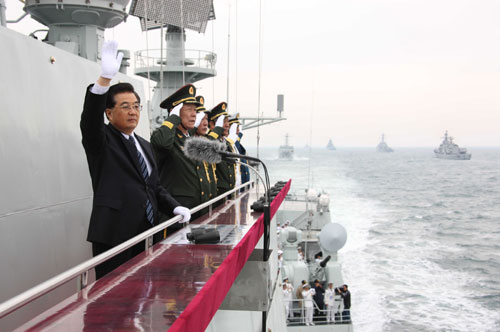 Chinese President Hu Jintao (L) waves to the navy vessels which are being reviewed while aboard the destroyer Shijiazhuang in waters off Qingdao, east China's Shandong Province, on April 23, 2009. A parade displayed 25 naval vessels and 31 aircrafts of the PLA Navy, including two nuclear submarines, as part of a celebration to mark the 60th anniversary of the founding of the PLA Navy.