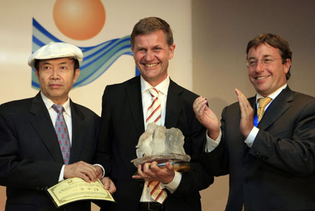 Achim Steiner(R1), under-secretary general of the United Nations and executive director of the UN environment programme (UNEP), and Chinese artist Yuan Xikun(L1), designer of the 2009 trophy, award Norwegian Environment Minister Erik Solheim with Policy Leadership Prize during the awarding ceremony of Champion of the Earth in Paris, on April 22, 2009.