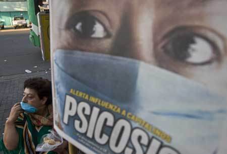 A woman wearing a mask walks past a poster calling on residents to prevent from being infected by the swine flu virus in the Mexico City, capital of Mexico, on April 25, 2009.