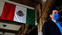 A man wearing a mask walks past a Mexican flag in Mexico City, capital of Mexico, on April 24, 2009. The government of Mexico City is launching a massive vaccination campaign throughout the city against swine flu, which has possibly killed dozens nationwide.