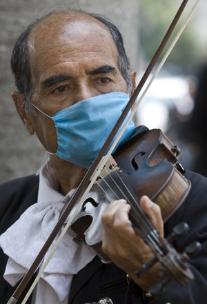 A Mexican busker wearing a mask plays the violin in Mexico City, capital of Mexico, on April 25, 2009.