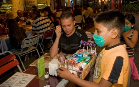 A boy wearing a mask sells candy at a restaurant in downtown Mexico City, capital of Mexico, on April 25, 2009.