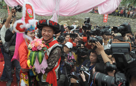 A new couple is surrounded by journalists at the Jina Qiang Ethnic Minority Village of Beichuan County, southwest China's Sichuan Province, on April 26, 2009. Twenty new couples held group wedding on Sunday. 