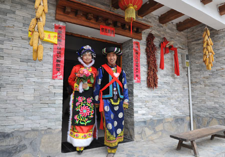 Bridegroom Tang Zhiguo (R) and his bride walk to attend wedding at the Jina Qiang Ethnic Minority Village of Beichuan County, southwest China&apos;s Sichuan Province, on April 26, 2009. Twenty new couples held group wedding on Sunday.