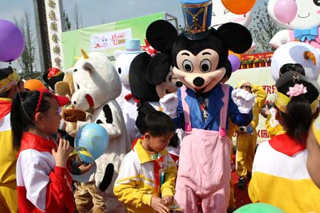 Cartoon star Mickey Mouse plays with children in a scenic spot of Nantong Horticulture Expo Park in Nantong, a city of east China's Jiangsu Province, on April 27, 2009.