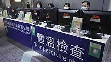 Staff members check the temperature of passengers with the help of machines at Hong Kong International Airport in Hong Kong, south China, on April 27, 2009. Hong Kong Special Administrative Region has taken measures to contain the possible spread of swine flu.