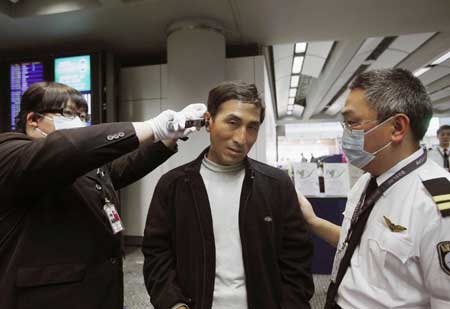 Staff members check the temperature of a passenger at Hong Kong International Airport in Hong Kong, south China, on April 27, 2009. Hong Kong Special Administrative Region has taken measures to contain the possible spread of swine flu. 