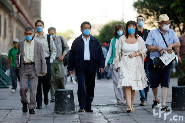 People wear surgical masks, to help prevent being infected with the swine flu, as they walk through the street on April 28, 2009 in Mexico City, Mexico. Reports indicate that most people confirmed with the new swine flu were infected in Mexico, where the number of deaths blamed on the virus has surpassed 150.