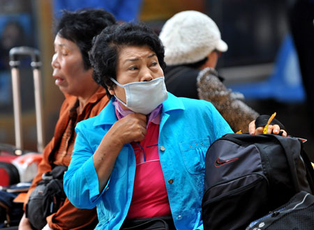 A masked passenger wait for body temperature checkup prior to her departure from the Tianhe Airport near Wuhan, capital city of central China&apos;s Hubei Province on April 28, 2009. 