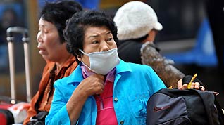 A masked passenger wait for body temperature checkup prior to her departure from the Tianhe Airport near Wuhan, capital city of central China's Hubei Province on April 28, 2009.