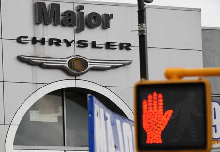 A walking stop sign is seen in front of the logo of Chrysler at a car dealership in New York, the United States, on April 7, 2009. The US Treasury will provide a further US$5 billion in loans to General Motors and US$500 million to Chrysler as the automakers work on their viability plans, officials said on Tuesday.