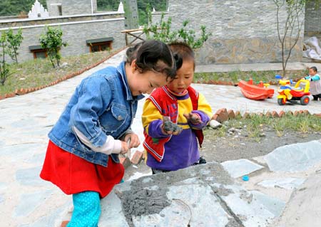 The picture taken on April 26, 2009 shows children of Qiang ethnic group play in front of a new house in Beichuan Qiang Autonomous County, southwest China's Sichuan Province. Life has resumed normal here after last May's devastating earthquake. People in the region are struggling for a better future.