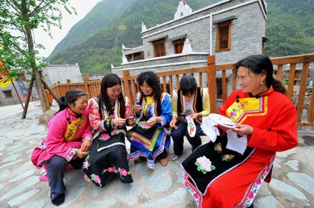 The picture taken on April 26, 2009 shows women of Qiang ethnic group make embroidery in front of a newly-built house in Beichuan Qiang Autonomous County, southwest China's Sichuan Province. Life has resumed normal here after last May's devastating earthquake. People in the region are struggling for a better future. 