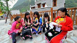 The picture taken on April 26, 2009 shows women of Qiang ethnic group make embroidery in front of a newly-built house in Beichuan Qiang Autonomous County, southwest China's Sichuan Province. Life has resumed normal here after last May's devastating earthquake. People in the region are struggling for a better future.