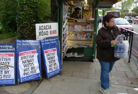 A pedestrian walks past placards of swine flu news at a newsstand in London, the United Kingdom, on April 28, 2009. Leaflets giving advices about the new H1N1 swine flu virus will be sent to every home in Britain, said the British Department of Health on April 29. A newly wed couple in Scotland have been tested positive for the infection of swine flu virus after returning from Mexico, and 22 other people are waiting for test results. 