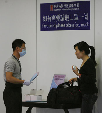 An airport staff supply face mask and propaganda paper to a visitor at Hong Kong International Airport in Hong Kong, south China, on May 1, 2009.