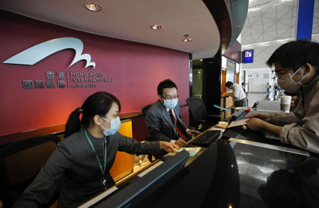 Staff of Hong Kong International Airport wear face masks as they serve a visitor in Hong Kong, south China, on May 1, 2009. 