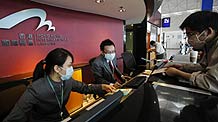 Staff of Hong Kong International Airport wear face masks as they serve a visitor in Hong Kong, south China, on May 1, 2009.