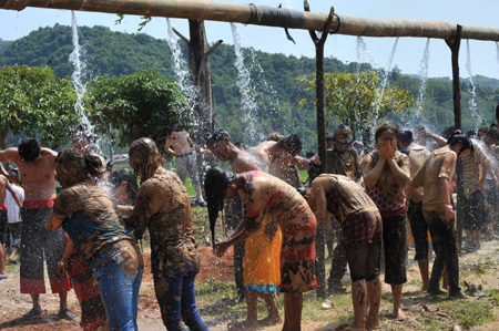 People covered with clay take a shower during a carnival at the Va Ethnic Autonomous Prefecture of Cangyuan, southwest China's Yunnan Province, May 2, 2009. During the 4-day festival, people daubing each other with the clay made of natural material, to express wishes of health and happiness. (Xinhua/Chen Haining)