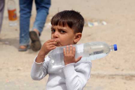 A Palestinian boy carries drinking water with a plastic bottle in the war-battered southern Gaza Strip town of Rafah, near the border with Egypt, on May 2, 2009. Palestinians face dire water shortages because of both bad Palestinian management and Israeli restrictions.