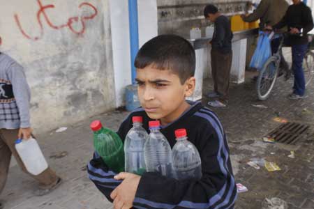 A Palestinian boy fetches drinking water with plastic bottles in the war-battered southern Gaza Strip town of Rafah, near the border with Egypt, on May 2, 2009.