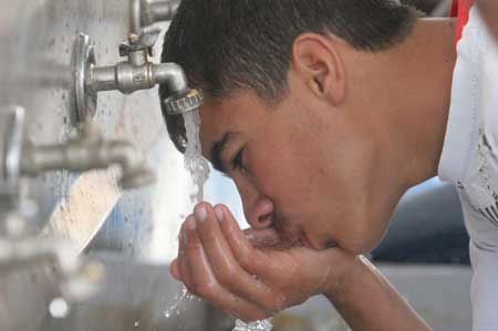  A Palestinian man drinks water under a water faucet in the war-battered southern Gaza Strip town of Rafah, near the border with Egypt, on May 2, 2009. 